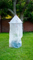 Load image into Gallery viewer, Tree Defender 6-foot plant protection system covering a young tree on a grassy lawn.