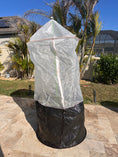 Load image into Gallery viewer, Skirted Tree Defender with a white breathable mesh cover, built-in front zipper, and black skirt secured around the base of a young tree.
