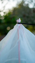 Load image into Gallery viewer, Close-up of a zip tie securing the breathable mesh Tree Defender cover around the top of the support stake.
