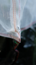 Load image into Gallery viewer, Close-up of the built-in zipper on the breathable mesh Tree Defender cover, providing easy access for watering, pruning, and plant care.

