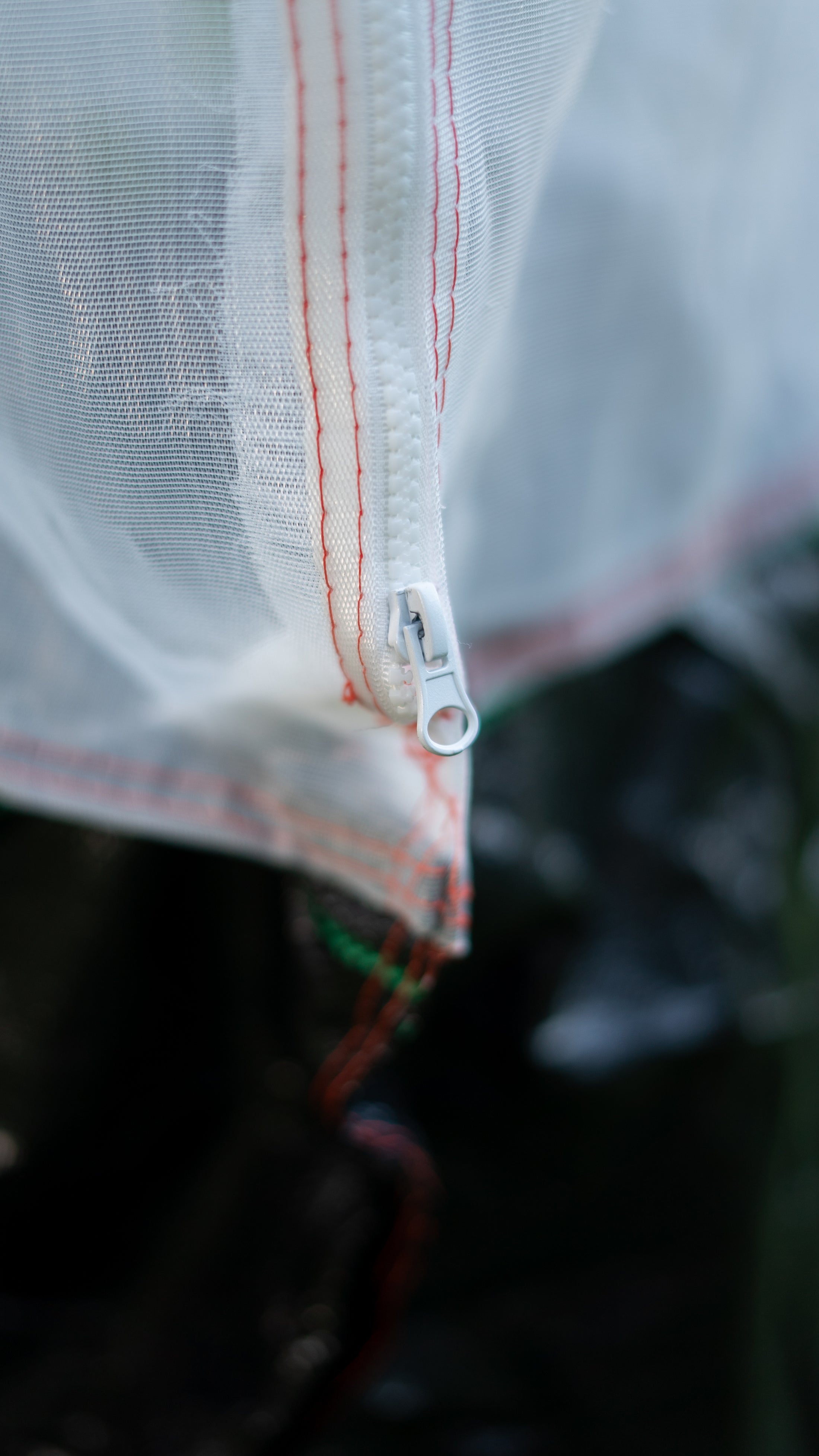 Close-up of the built-in zipper on the breathable mesh Tree Defender cover, providing easy access for watering, pruning, and plant care.